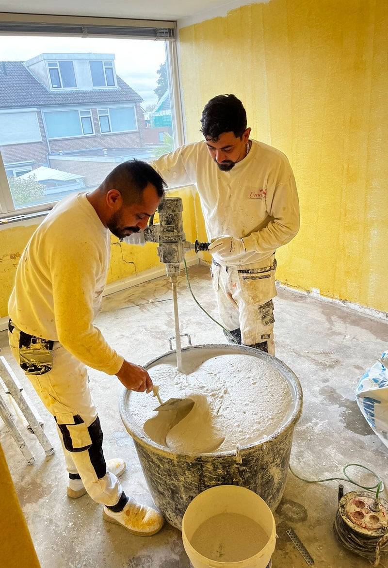 Twee vakmannen van Umut58 mengen specie op de werkvloer
